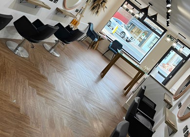 Elegant salon interior at Hair By HM at Chique, Mapplewell, England, GB, displaying modern styling chairs and mirrors.