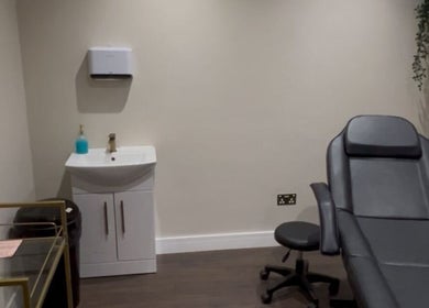 A modern treatment room at Aesthetica Nails & Aesthetics in Iver, England, GB, featuring a sleek chair and sink.
