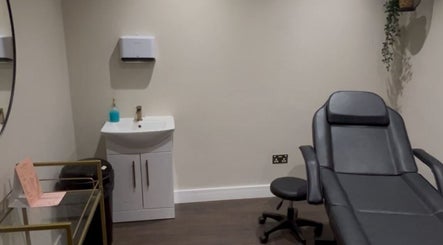 A modern treatment room at Aesthetica Nails & Aesthetics in Iver, England, GB, featuring a sleek chair and sink.