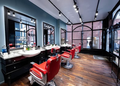 Elegant interior of Usta Barbers in London, England with stylish red chairs and large windows.