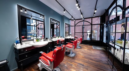 Elegant interior of Usta Barbers in London, England with stylish red chairs and large windows.