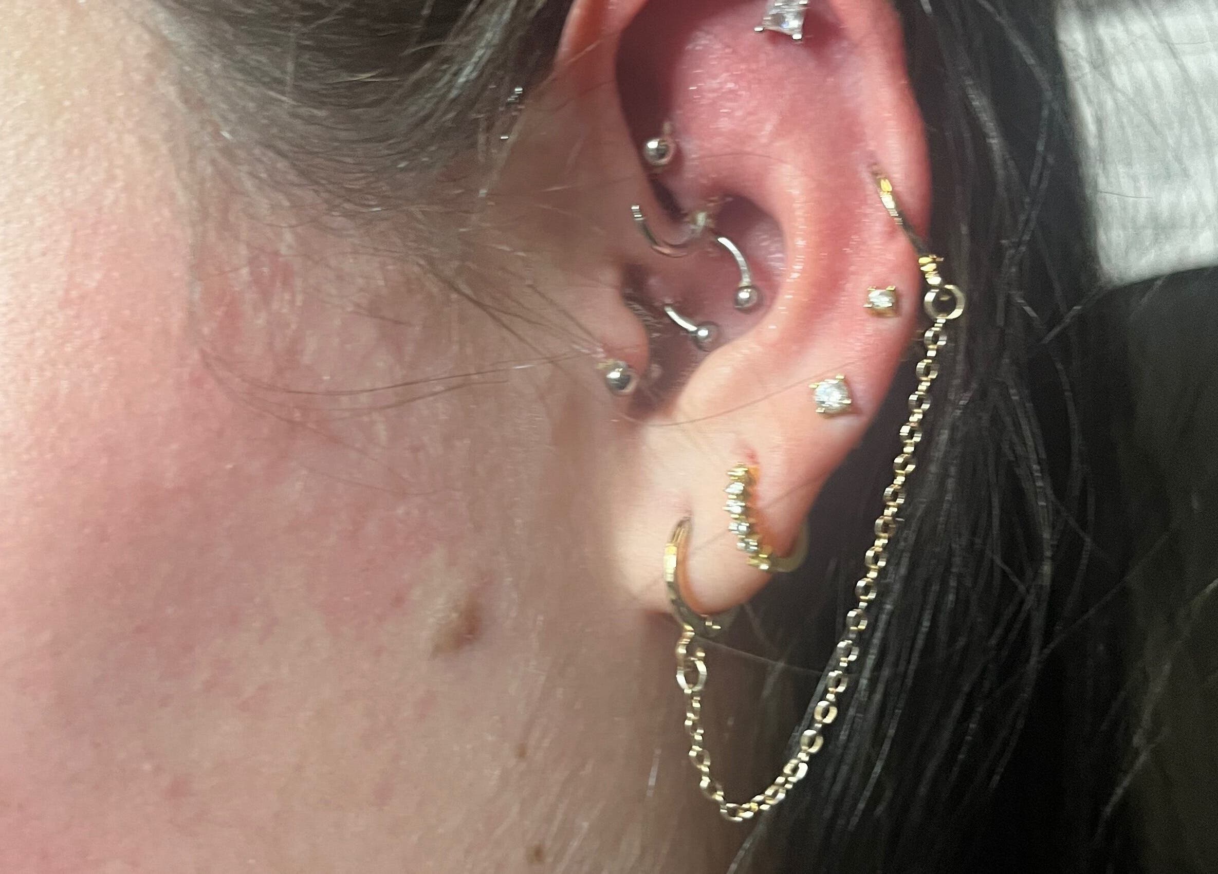 Intricate ear piercings with gold jewelry showcased at IVRY, Pawling, New York, US.