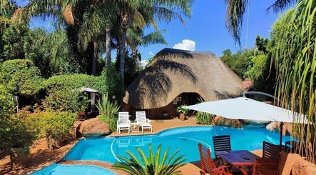 Outdoor pool at Francor Guesthouse & Spa in Akasia, Gauteng, ZA, surrounded by lush greenery and thatched roof.