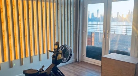 Bright fitness room at Wellbeing with Lucy in Birkenhead, England, GB, featuring a rowing machine and city view.
