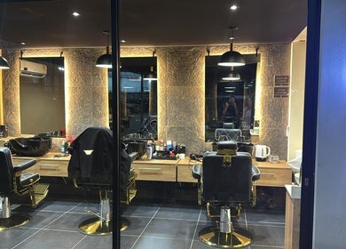 Interior moderno de ELITE BARBER NAILS en Envigado, Antioquia, CO con sillas de barbero y espejo luminoso.