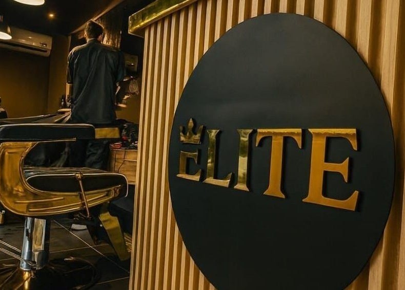 Interior de Elite Barber Nails en Envigado, Antioquia, CO, mostrando sillas doradas y logotipo elegante.