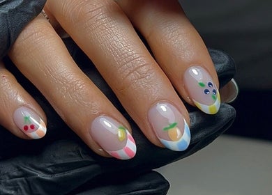 Fruit-themed nail art design at HT Studio in Glasgow, Scotland, GB. A close-up of a hand with colorful patterns.