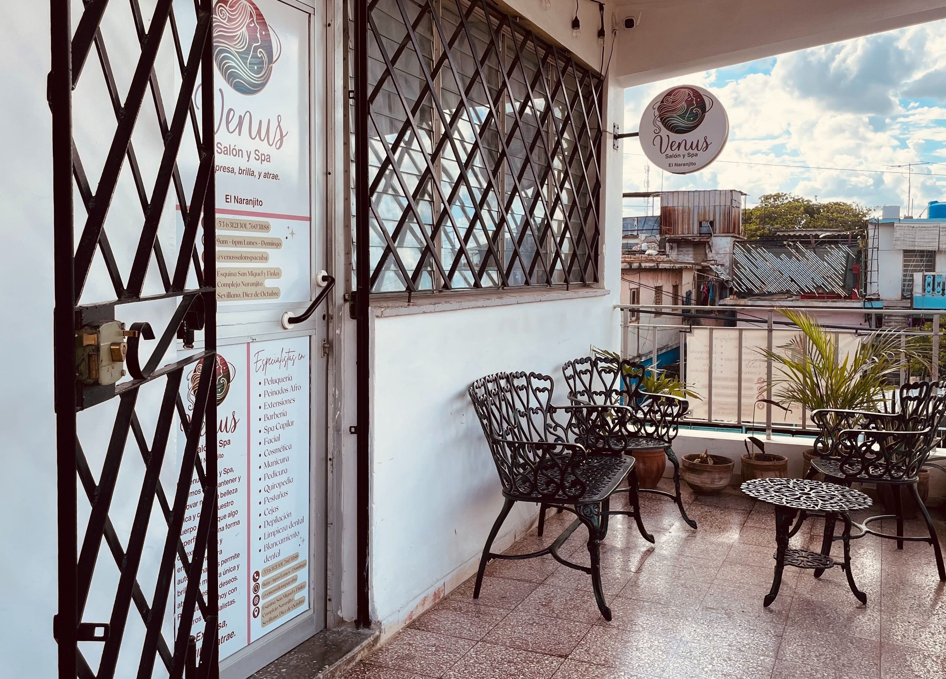 Entrada del Venus Salón y Spa, El Naranjito en 10 de Octubre, La Habana, con sillas de hierro y vistas urbanas.