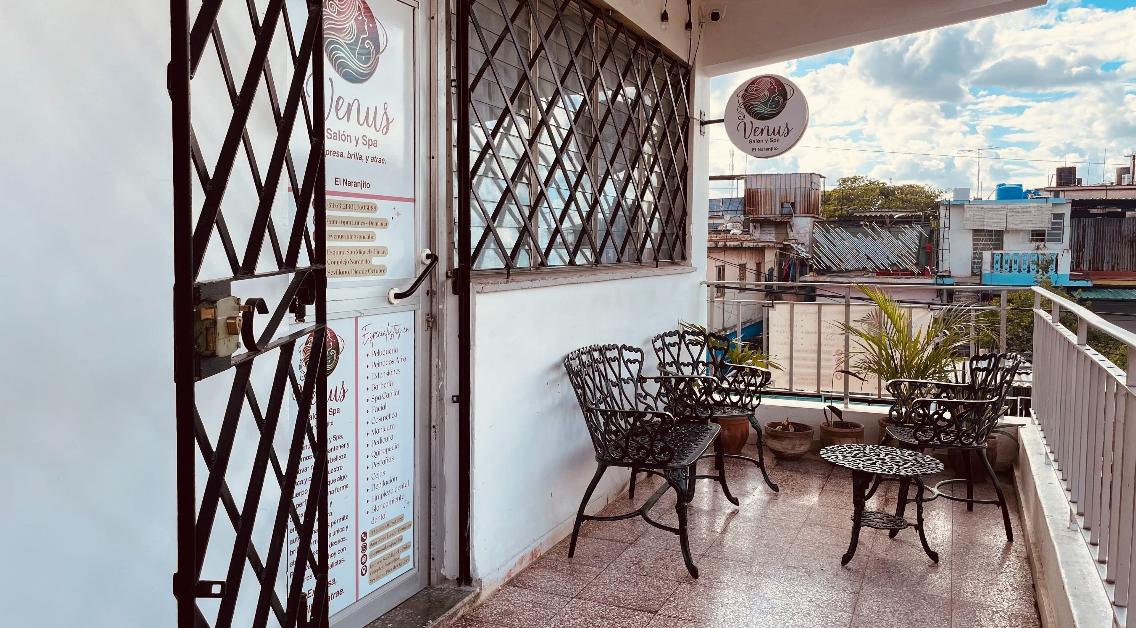 Entrada del Venus Salón y Spa, El Naranjito en 10 de Octubre, La Habana, con sillas de hierro y vistas urbanas.