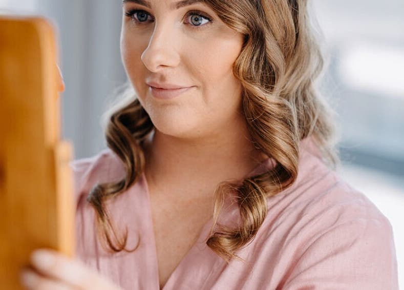 Woman in pink robe checking hair at The Studio, Paraparaumu Beach, Wellington Region, NZ.