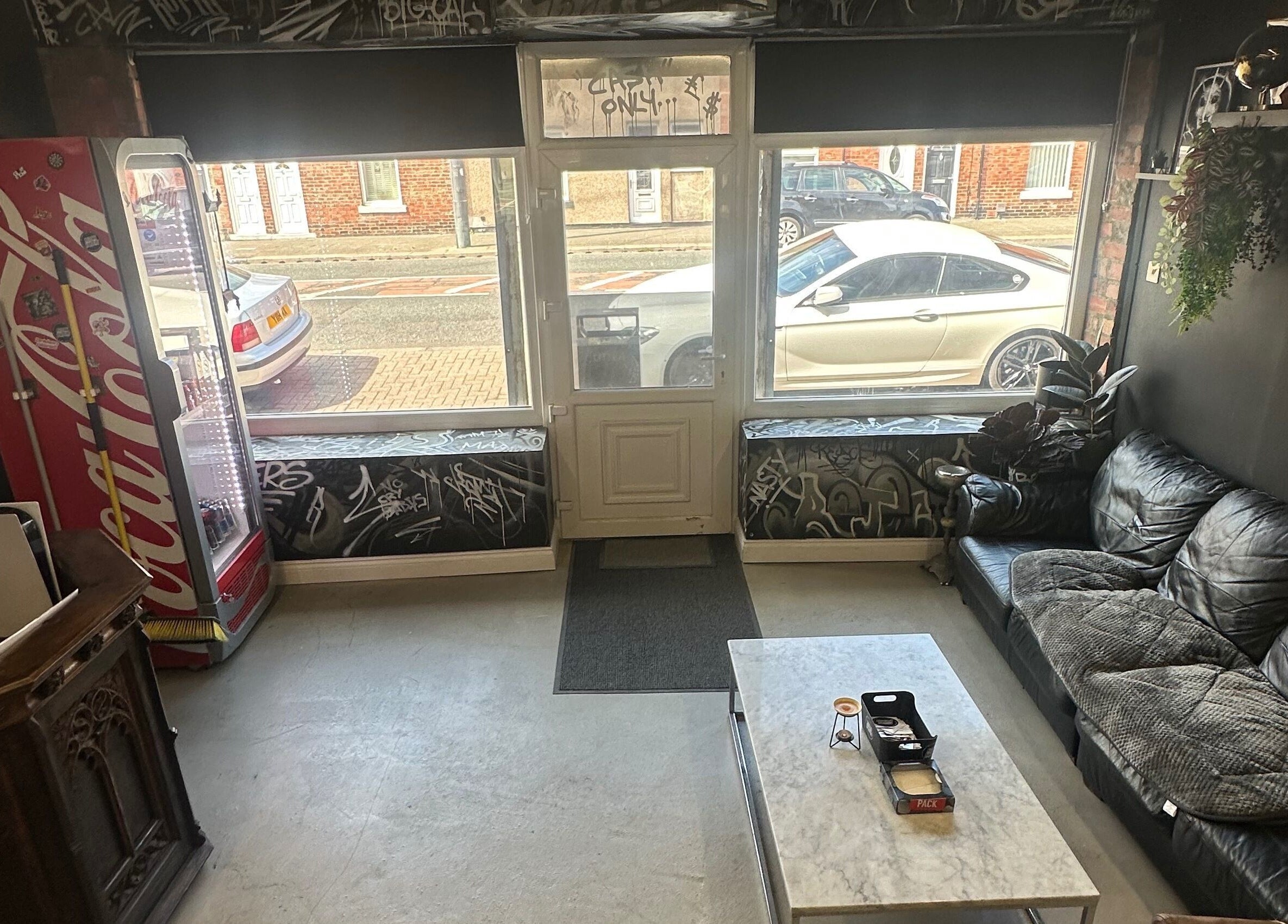 Cozy interior of Rejects Barbers in Boldon Colliery, England, GB featuring leather sofas and street art decor.