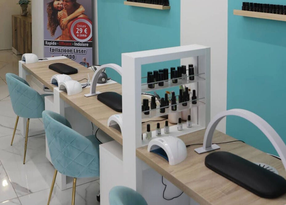 Postazione manicure moderna da Frida Nails a Roma, Lazio, IT, con sedie blu e smalti in esposizione.