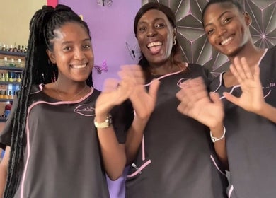 Smiling team at Chan's Unique Hair Studio, Kingstown, St. George, VC, waving in a welcoming gesture.