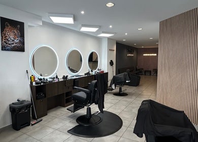 Intérieur élégant du salon Sniperkut à Genève, Genève, CH avec des miroirs circulaires et des fauteuils de coiffure.