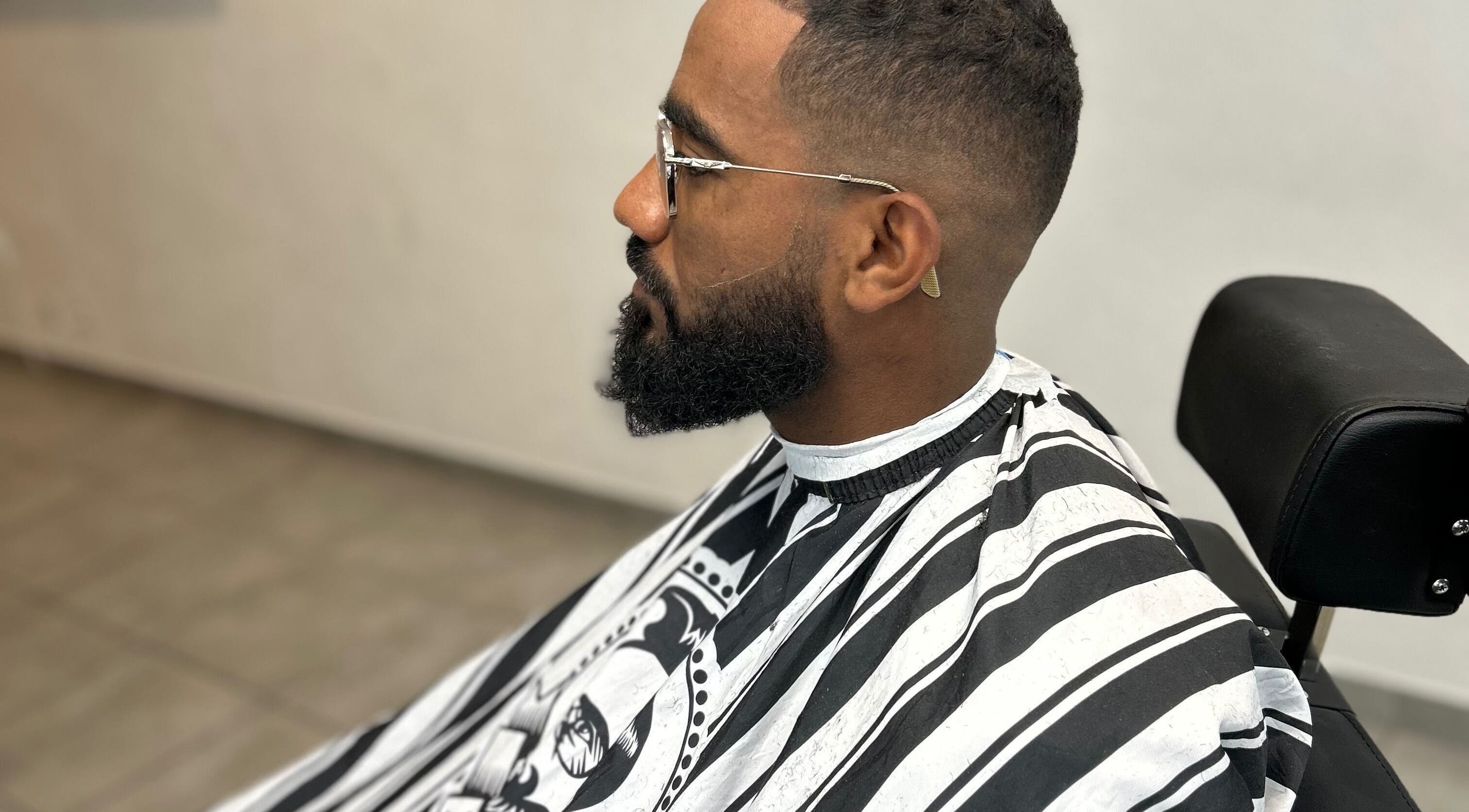 Client chez Kinstar à Genève, Genève, CH, recevant une coupe élégante dans un fauteuil de barbier moderne.