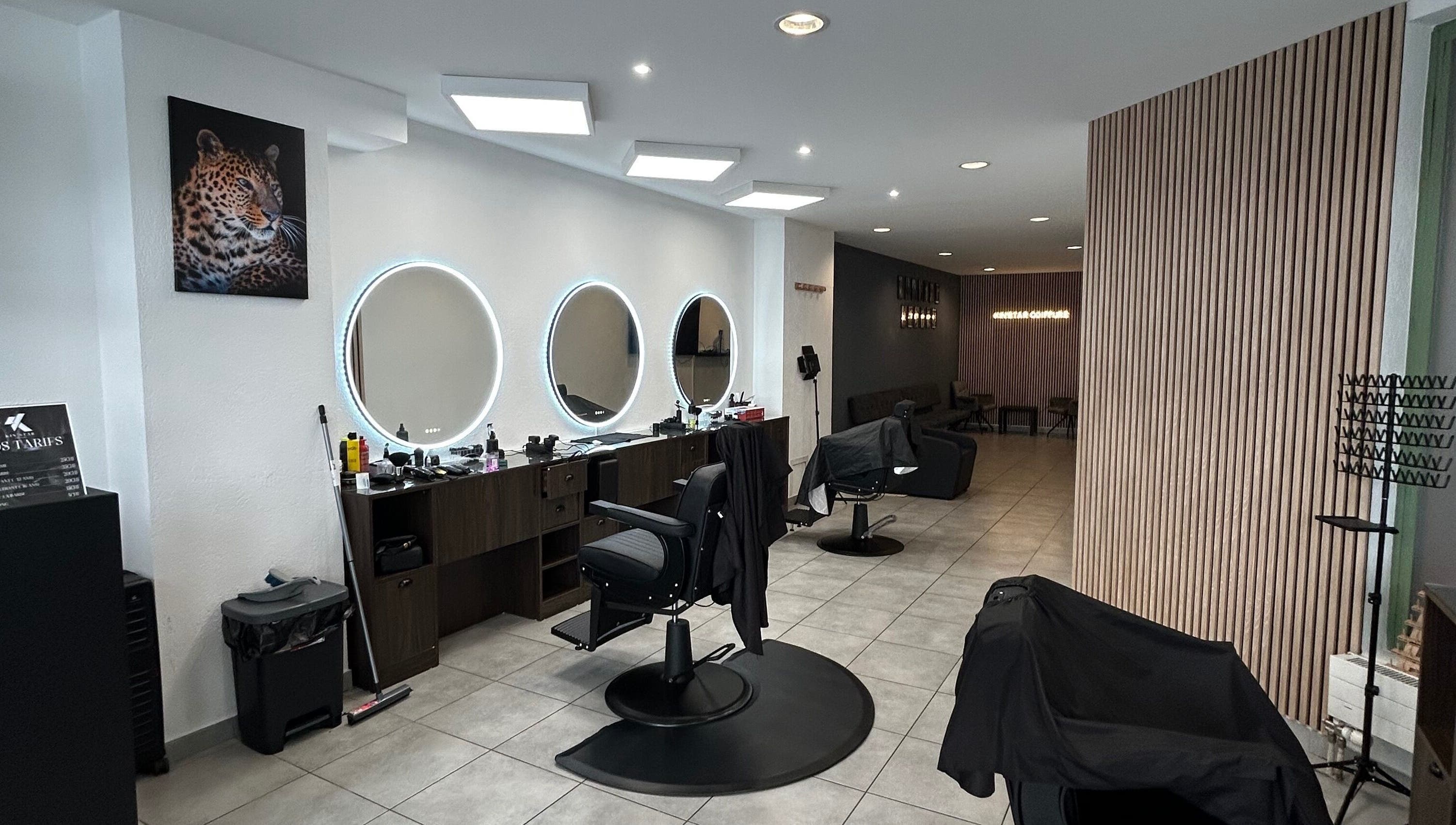 Intérieur moderne du salon Kin'star, Genève, avec fauteuils stylisés et miroirs ronds lumineux.