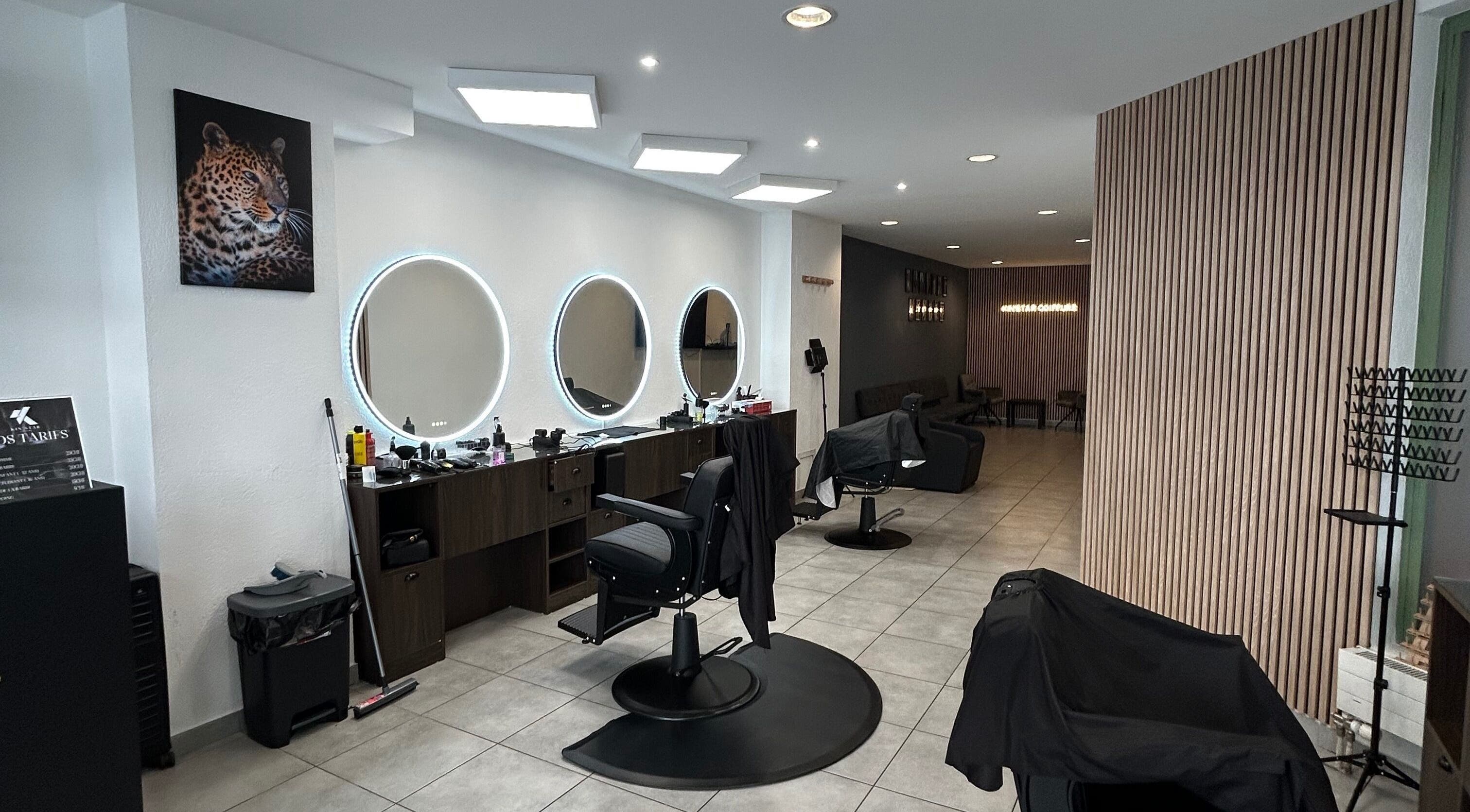Intérieur moderne du salon Kin'star, Genève, avec fauteuils stylisés et miroirs ronds lumineux.
