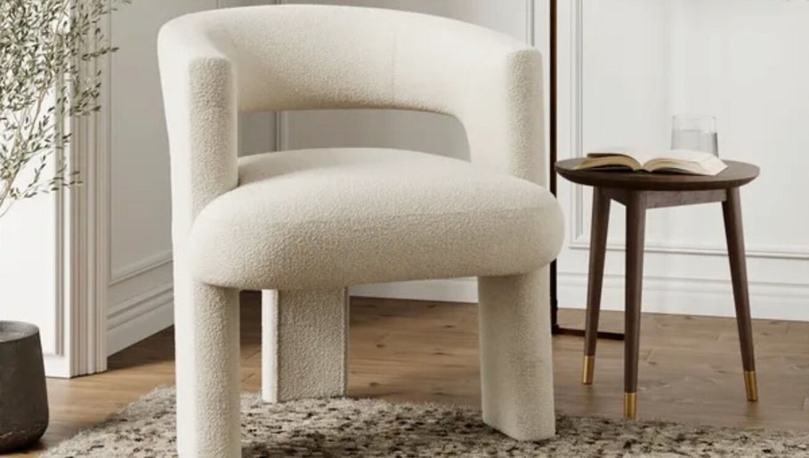 A plush white chair beside a round wooden table at The Little Gel Studio, Poole, England, GB.