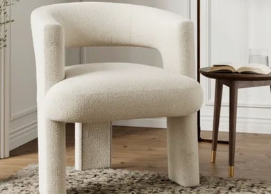 A plush white chair beside a round wooden table at The Little Gel Studio, Poole, England, GB.