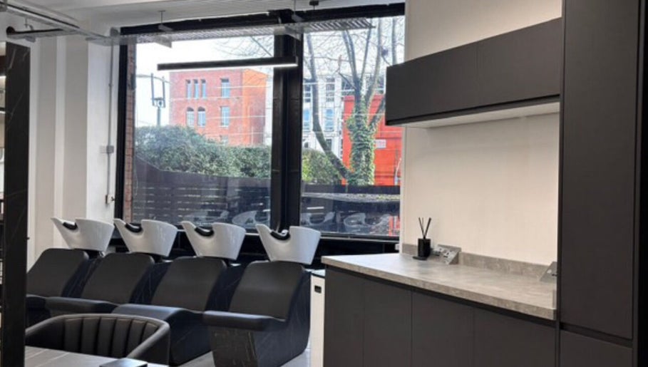 Modern shampoo station at Olivermarshair, Manchester, England, GB, with sleek black chairs and large windows.