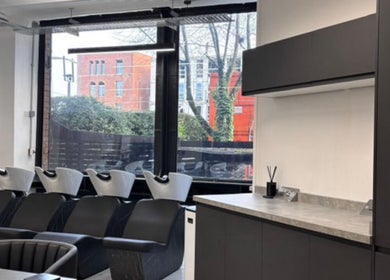 Modern shampoo station at Olivermarshair, Manchester, England, GB, with sleek black chairs and large windows.