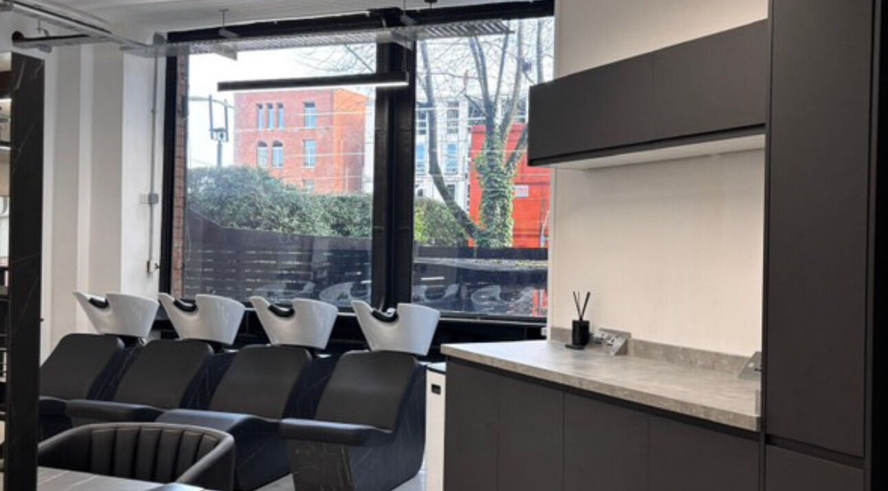 Modern shampoo station at Olivermarshair, Manchester, England, GB, with sleek black chairs and large windows.