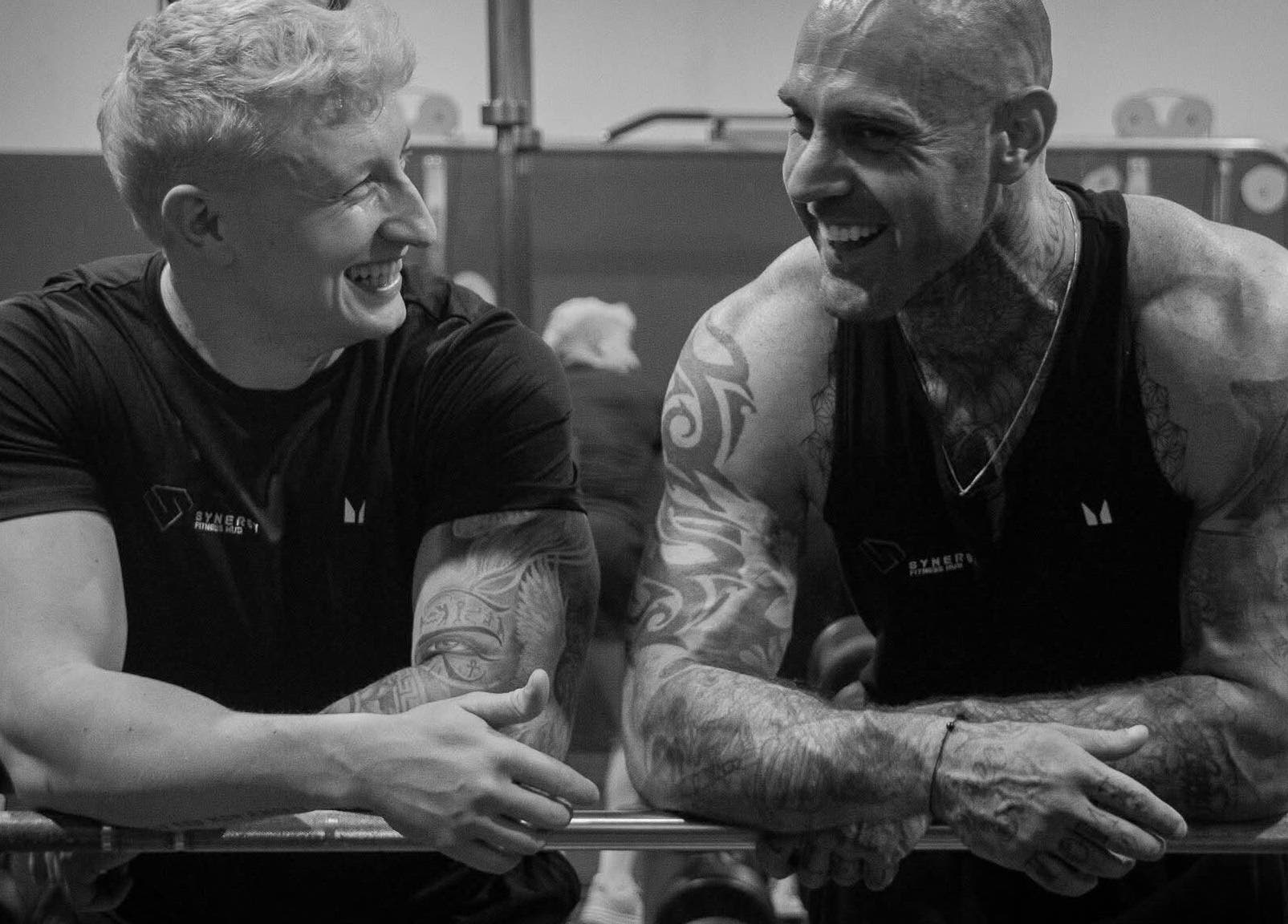 Two men sharing laughter and workout at Synergy Fitness Hub, Amlwch, Wales, GB.