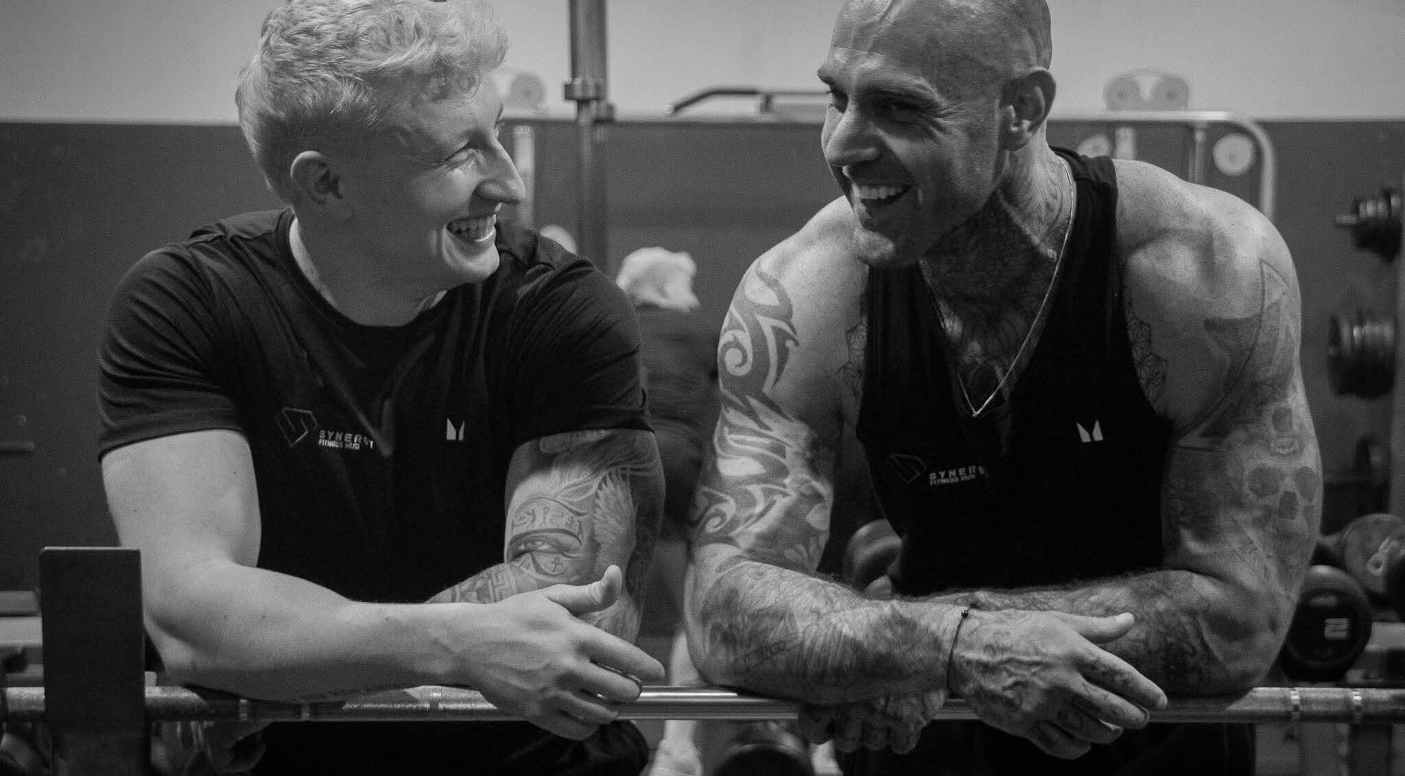 Two men sharing laughter and workout at Synergy Fitness Hub, Amlwch, Wales, GB.