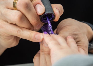 Nail painting in progress at Pick Your Color Nail Salon, Chicago, IL, US with vibrant purple polish.