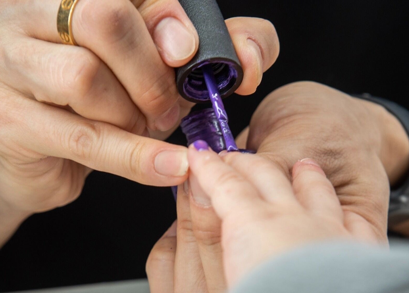 Applying purple nail polish at Pick Your Color Nail Salon, Chicago, IL, US, showcasing expert care.