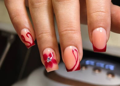 Elegant floral nail art captured at Kyuote_Nails, Rīga, LV, featuring red tips and blossoms.