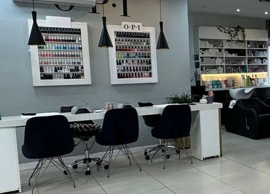 Interior de The Factory Afro Curly Santo Domingo con mesas de manicura y sillas modernas en Santo Domingo, Heredia, CR.
