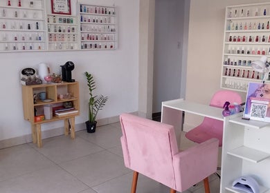 Interior moderno do Talidelpuponails em São Paulo, com poltronas rosas e esmaltes organizados.