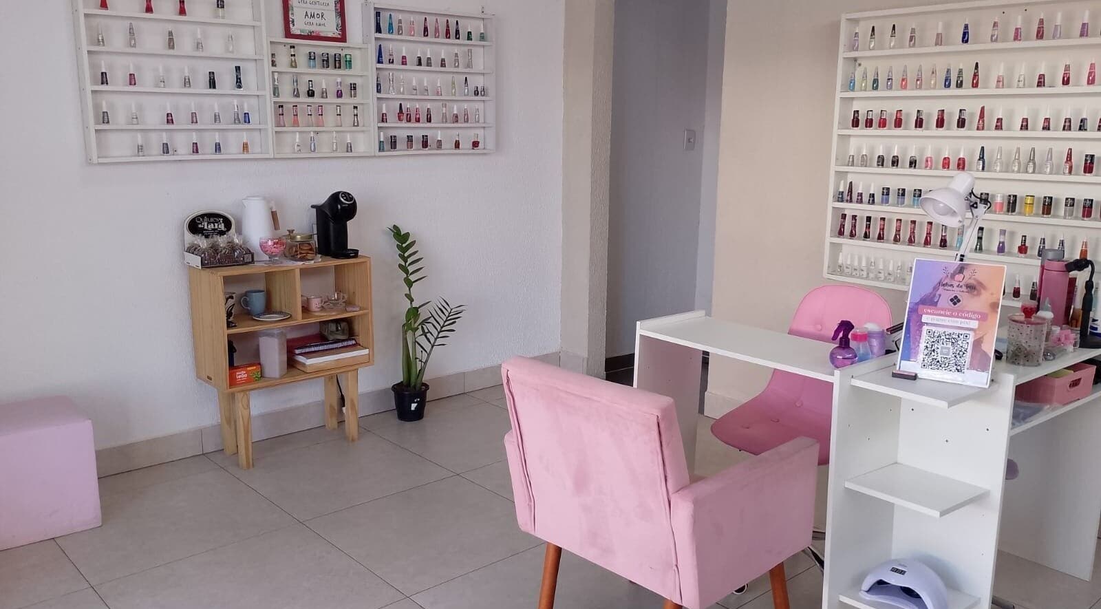 Interior moderno do Talidelpuponails em São Paulo, com poltronas rosas e esmaltes organizados.