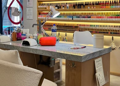 Mesa de manicura en The Nail Shop - The Brow + Lashes Bar, Ciudad De México, con esmaltes de uñas.