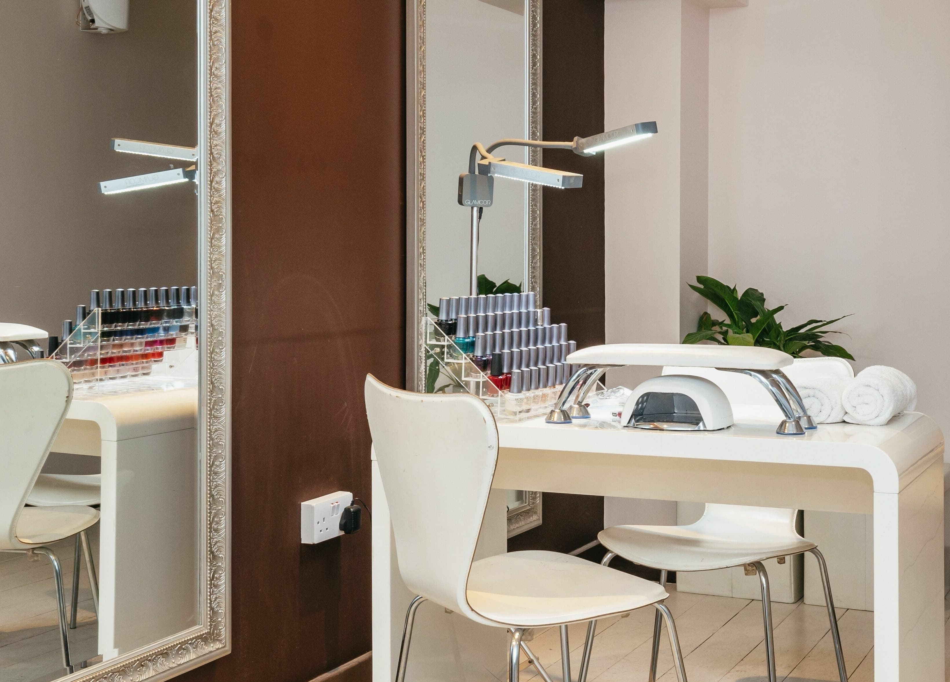 Modern nail station at Decadence Hair and Beauty, London, England, GB, featuring a mirror and polish display.