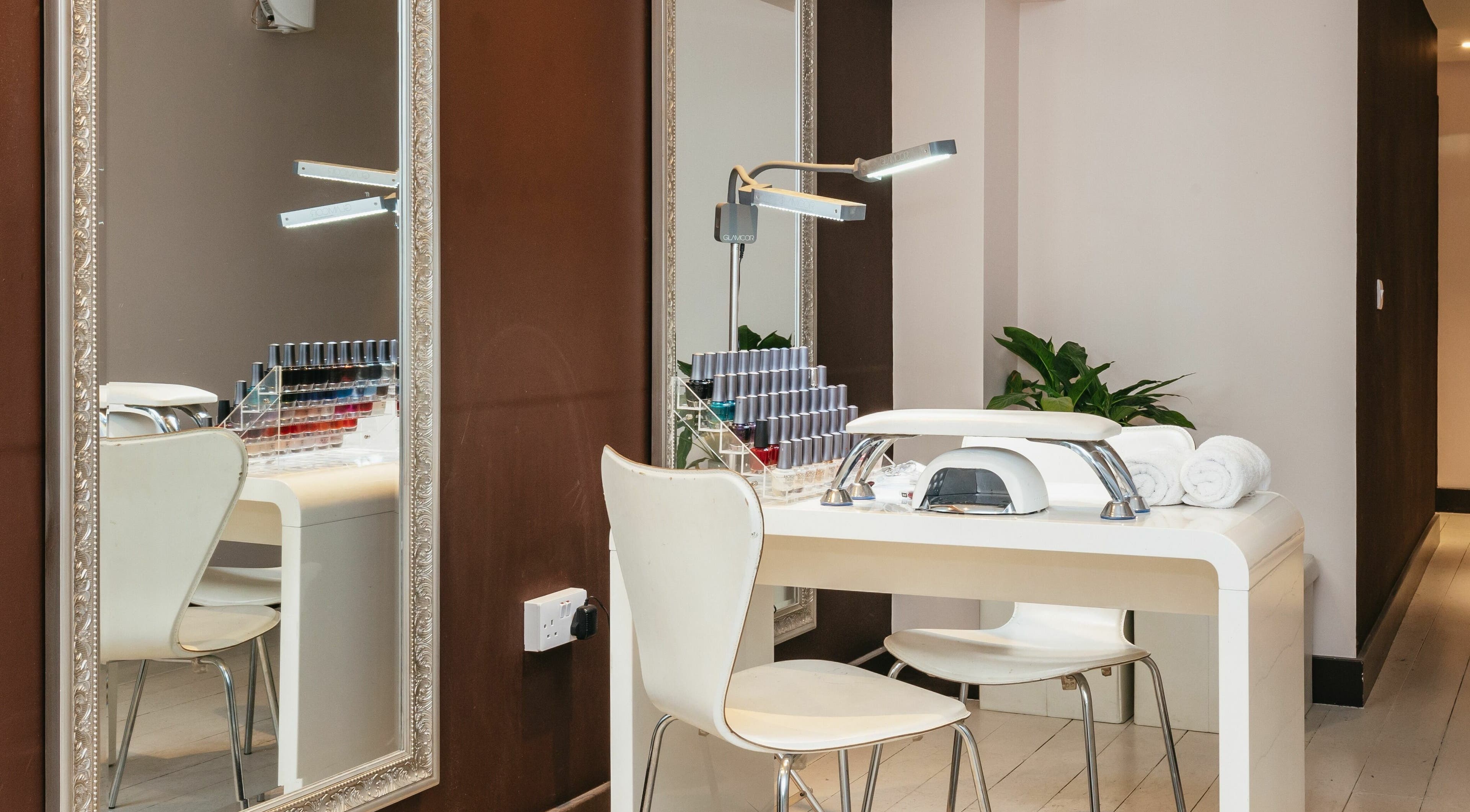 Modern nail station at Decadence Hair and Beauty, London, England, GB, featuring a mirror and polish display.