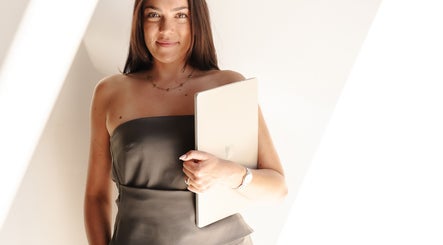 Professional woman at Beja Aesthetics, Rosebery, New South Wales, AU, holding a laptop in bright setting.