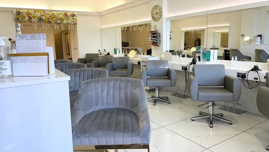 Chic beauty salon interior at Laurens d'Auray, Grays, England, GB with plush grey chairs and modern decor.