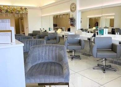 Chic beauty salon interior at Laurens d'Auray, Grays, England, GB with plush grey chairs and modern decor.