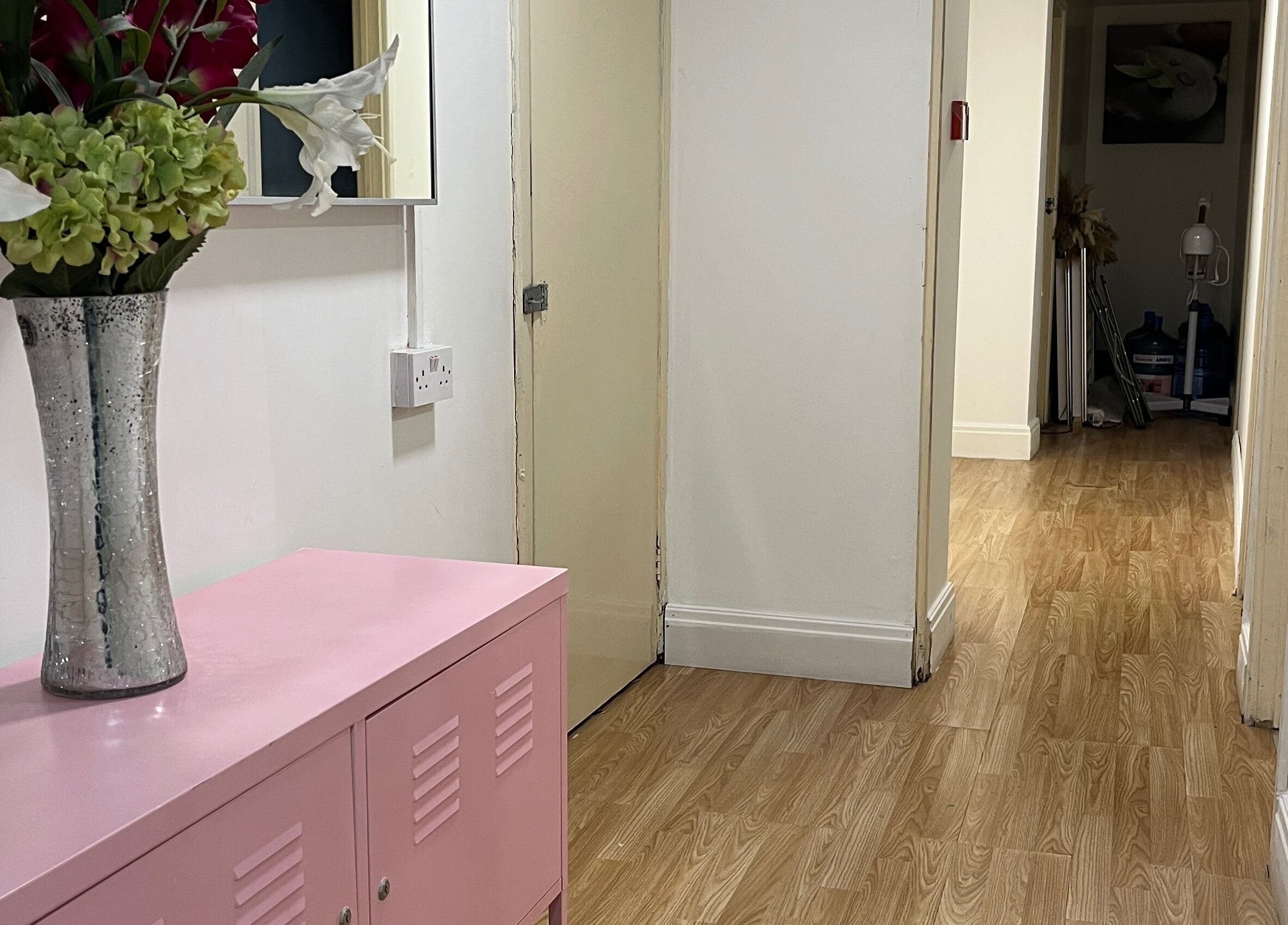 Elegant hallway at Evellere Sugar Waxing in Bromley, England, GB, featuring wooden floors and a floral vase.