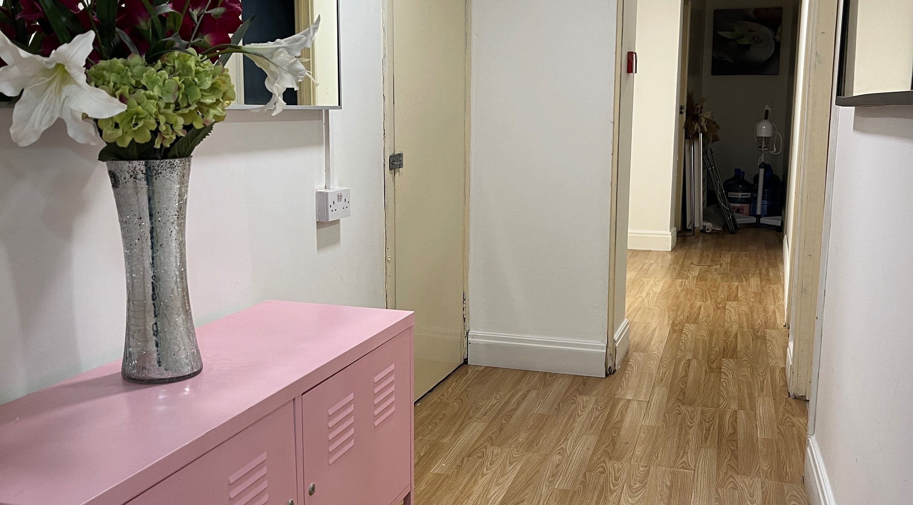 Elegant hallway at Evellere Sugar Waxing in Bromley, England, GB, featuring wooden floors and a floral vase.