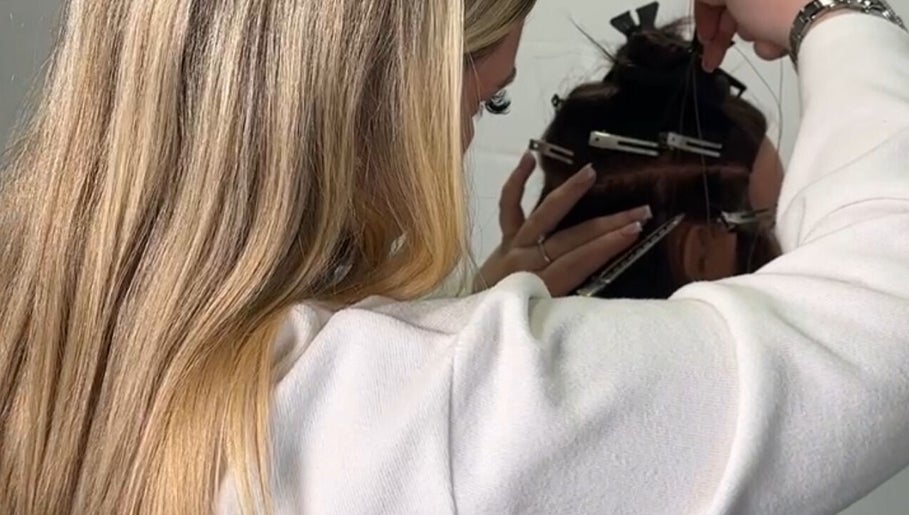 Stylist at EM Hair, Seaton Delaval, England, GB meticulously attaching hair extensions.