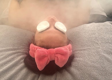 Relaxing facial steam at Serene Bliss by Kiera in Colwyn Bay, Wales, GB with a pink headband and soothing pads.