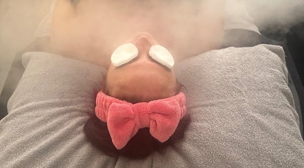 Relaxing facial steam at Serene Bliss by Kiera in Colwyn Bay, Wales, GB with a pink headband and soothing pads.