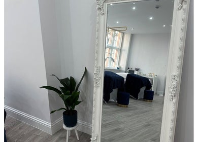 Elegant beauty room at Hennylash, London, England, GB, with a large ornate mirror and potted plant.