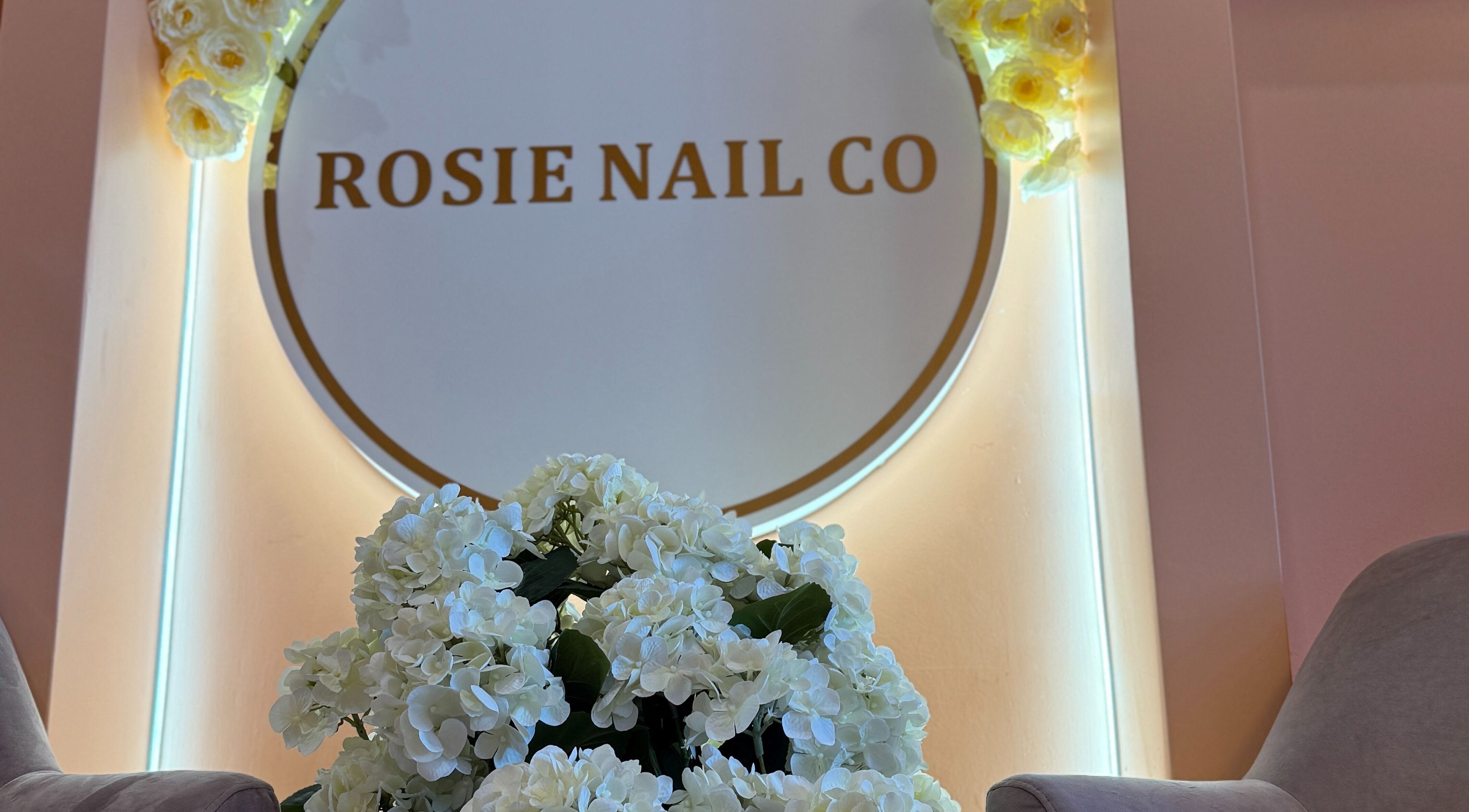 Rosie Nail Co welcomes guests in Melbourne with elegant white florals and a stylish logo display.