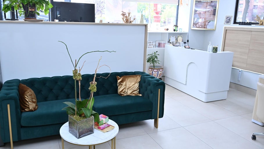 Luxurious lounge area at Laura's Beauty Touch, Rego Park, NY, featuring a green velvet sofa and chic decor.