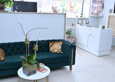 Luxurious lounge area at Laura's Beauty Touch, Rego Park, NY, featuring a green velvet sofa and chic decor.