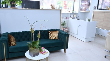 Luxurious lounge area at Laura's Beauty Touch, Rego Park, NY, featuring a green velvet sofa and chic decor.